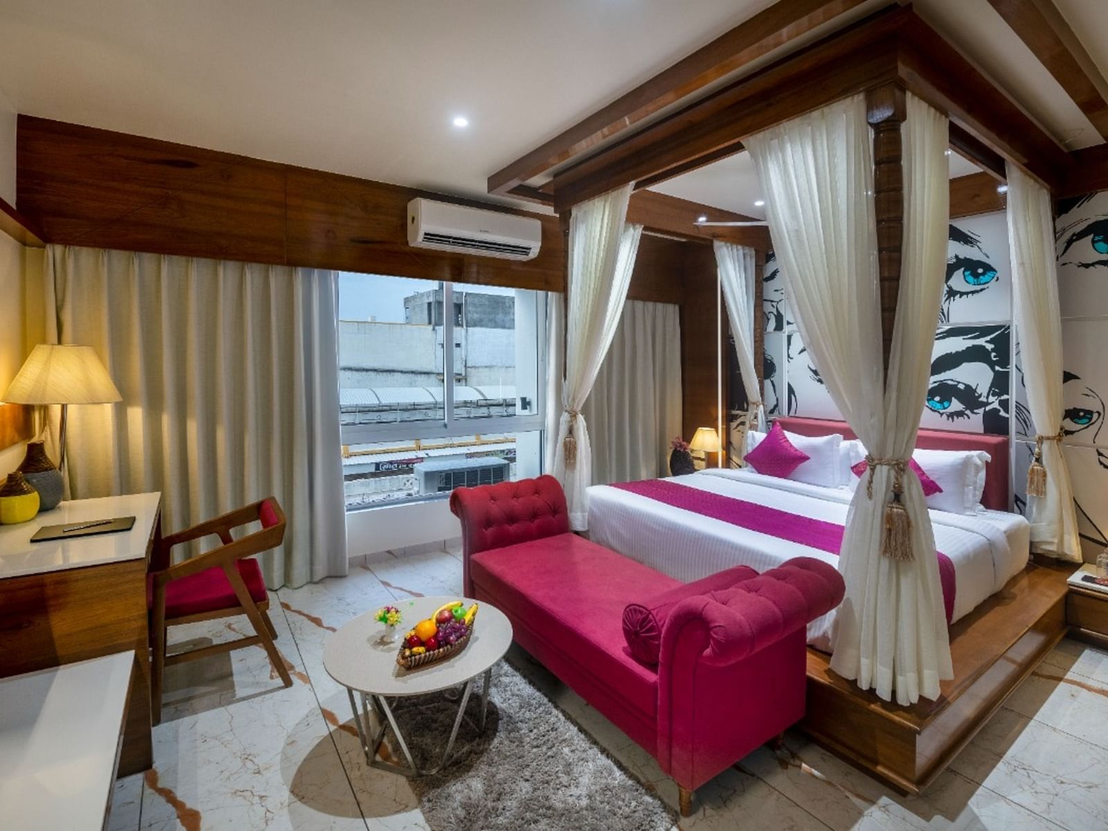 A room with a spacious bed, a small table with chairs, and a window with curtains at Angel Lords Eco Inn Amreli.