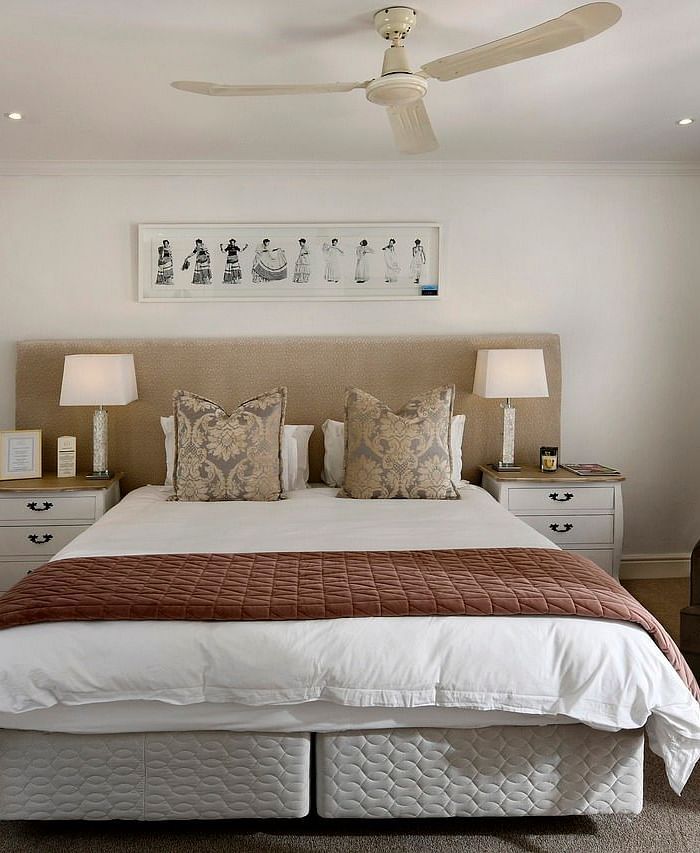 A double bed with a ceiling fan hanging over it in a bedroom.