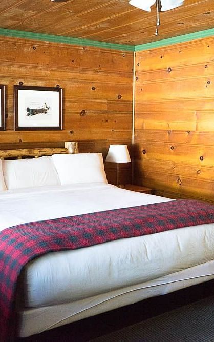 A room with a double bed and wooden panelling throughout at Shaver Lake Village Hotel.