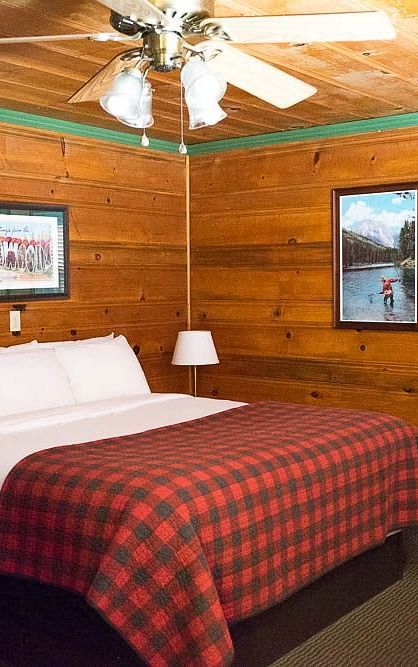 A room with a double bed and wooden panelling throughout at Shaver Lake Village Hotel.