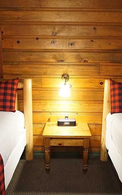 A room with twin beds and a side table placed in between them at Shaver Lake Village Hotel.