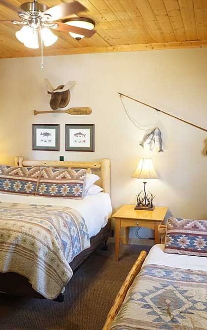 A room with a double bed, side tables, and wooden panelling on the ceiling at Shaver Lake Village Hotel.