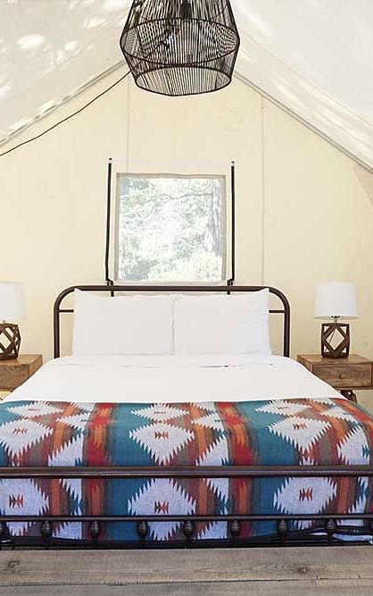 A tent with zip-down windows and a double bed placed in the middle at Shaver Lake Village Hotel.