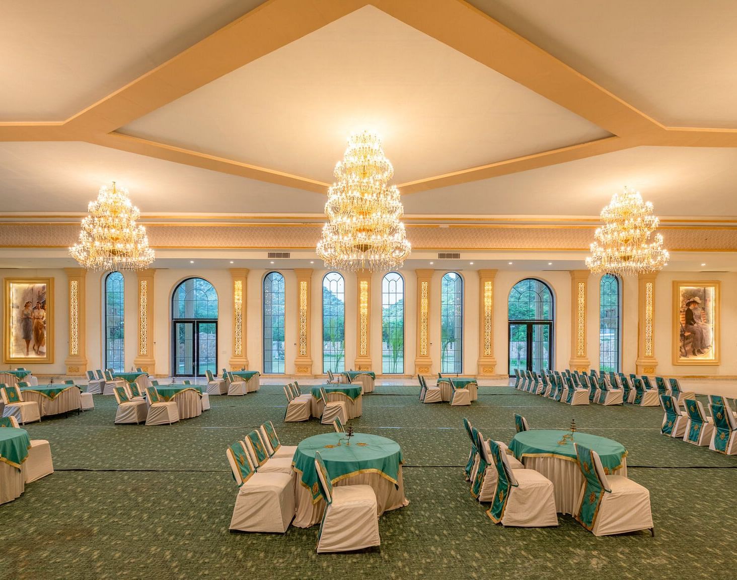 Side view of a banquet hall featuring round tables with chairs and chandeliers elegantly hanging from the ceiling at Valley by Grassfield.