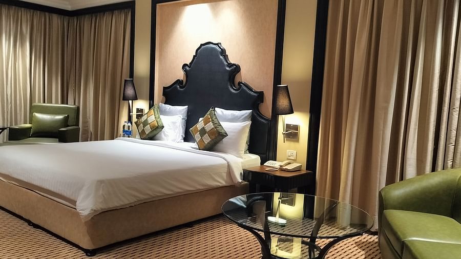  Premium hotel room featuring a large bed, lounge seating, curtains, and ambient lighting.