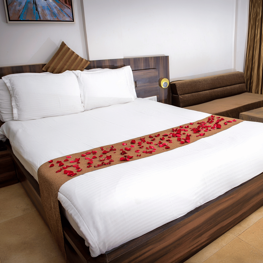 A close up view of the bed in Regent Room with its sofa and glass doors that lead to the balcony.