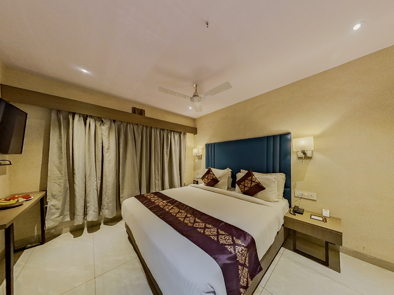 Luxurious double bed hotel room at Lords Eco Inn Dahej with blue headboard, modern amenities, flat-screen TV, and contemporary decor