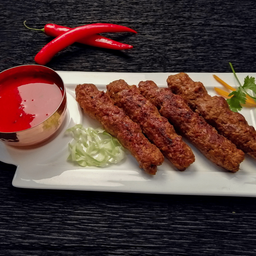 The seekh kebab with sauce and garnished with veggies.