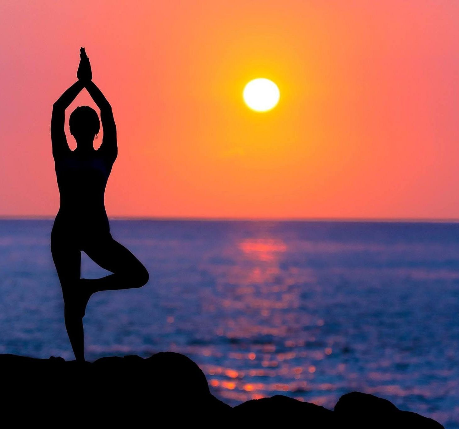 Image of  a person doing yoga with the sun in front