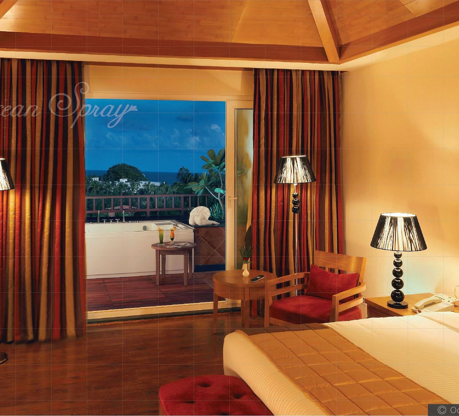 a double bed with side lamps and a tv opposite the bed inside Heavens at Ocean Spray, Puducherry.