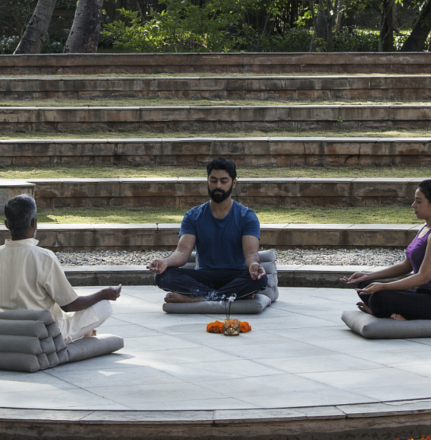 A group of people practising meditation in the centre of an amphitheatre 