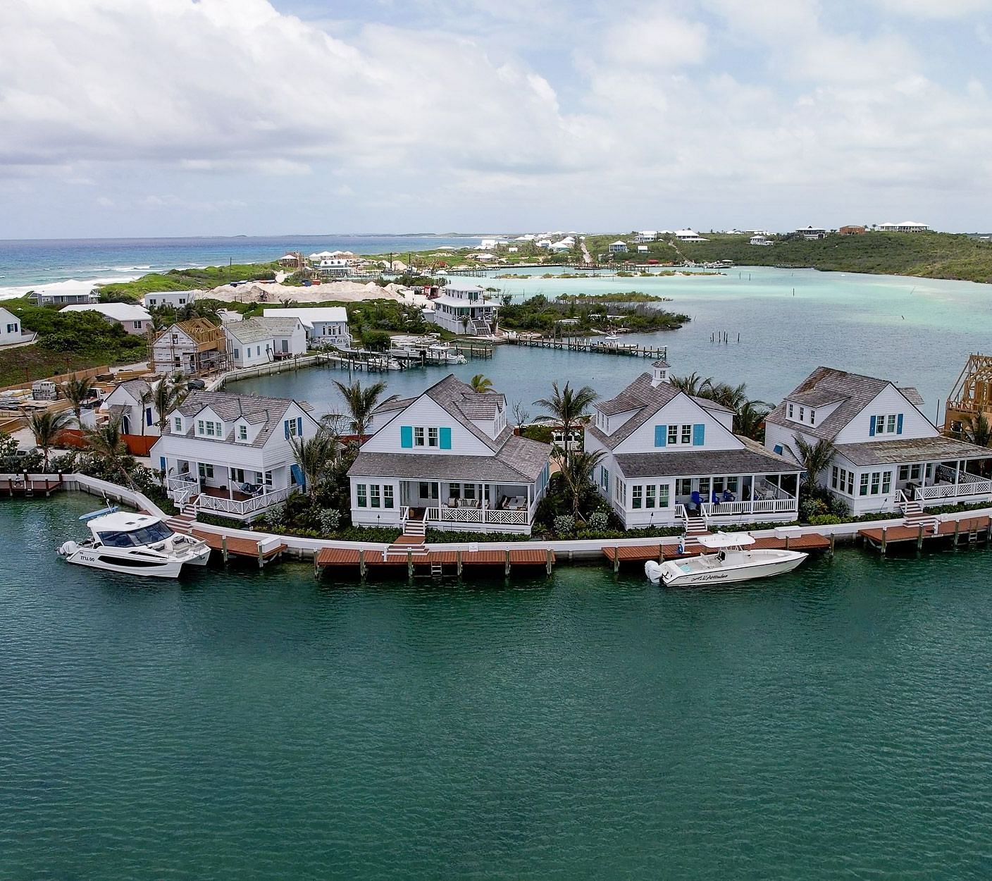 Marina scene with small boats docked near a group of seaside cottages and overwater villas in a protected inlet | Abaco Inn