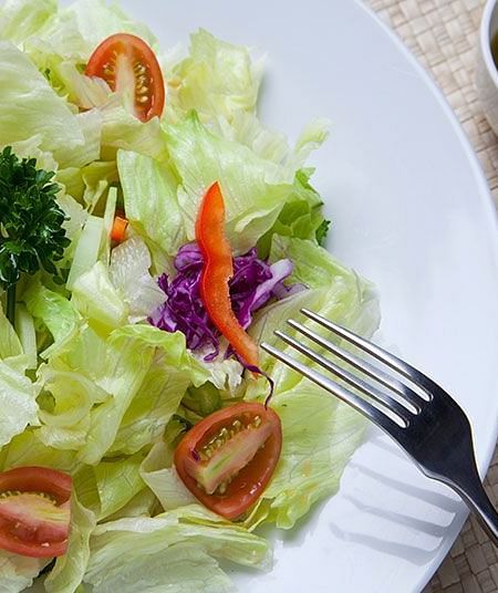 A close-up of a salad with lettuce, tomatoes, and herbs - Shreyas Retreat