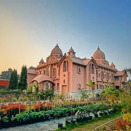 Majestic pink palace surrounded by lush gardens and vibrant flowers under a clear, colourful sky