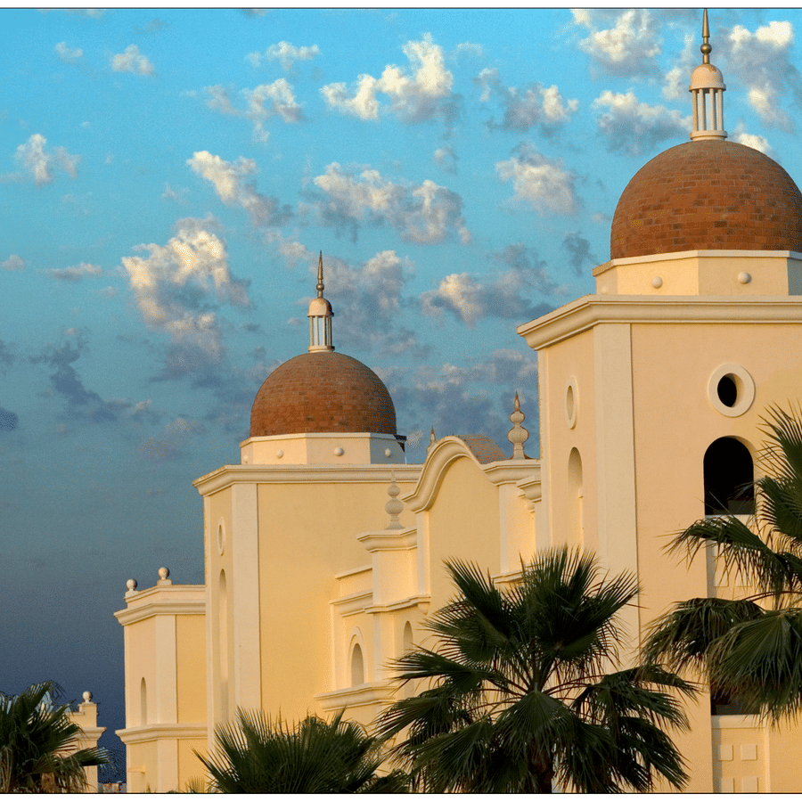 facade view of Cabo Palace Cabo with white clouds on blue skies in the background
