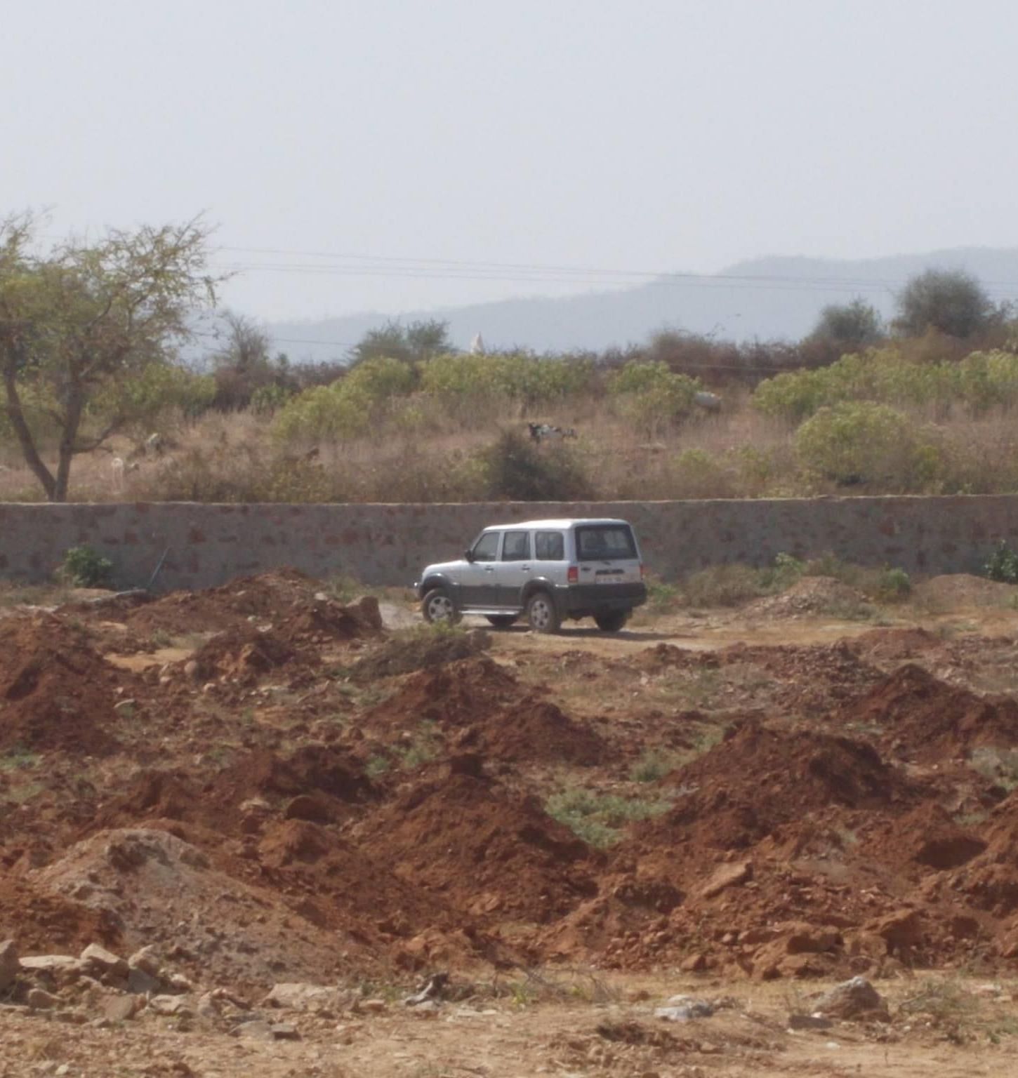An image of an arid land with a jeep parked on the road - Utsav Camp Sariska