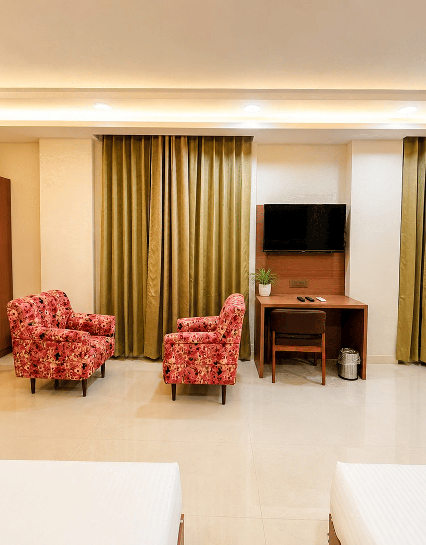 Jal Mahal Family Suite living area with a wardrobe, 2 armchairs and a wall-mounted TV at Lime Tree Hotel & Banquet, Jaipur