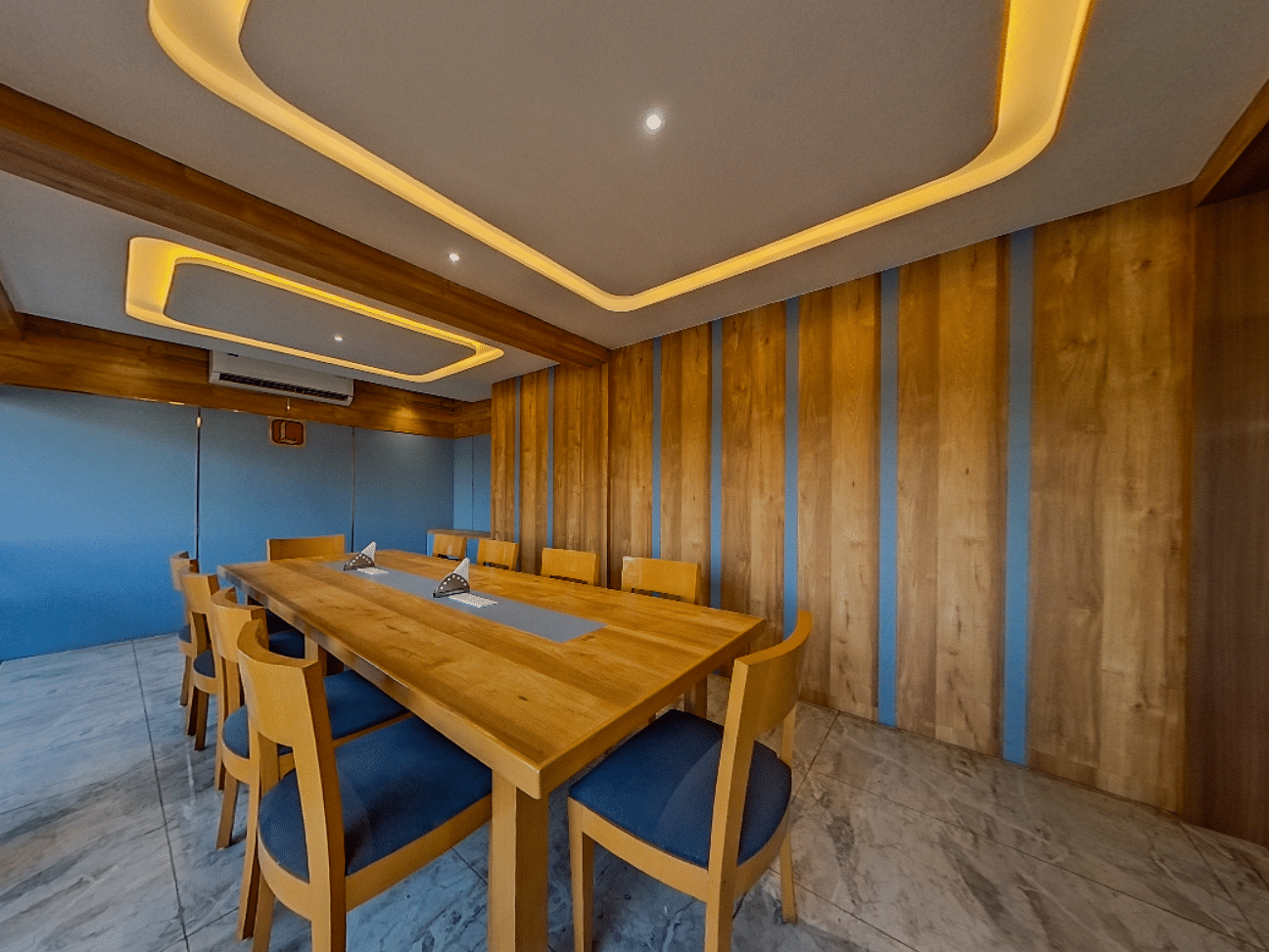 Elegant conference room at Lords Eco Inn Dahej with wooden paneling, blue upholstered chairs, and modern lighting for corporate meetings