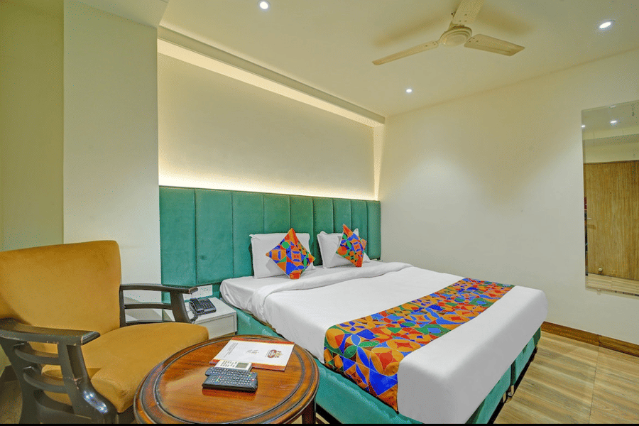 Stylish twin bedroom with vibrant bed runner, cozy seating and modern decor at Hotel Maurya, Bhopal.