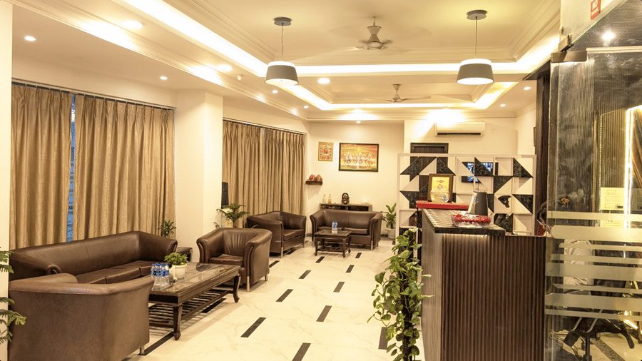 A comfortable waiting area at Hotel Apple Park Delhi with leather seating, patterned tiles, and large windows with neutral curtains.