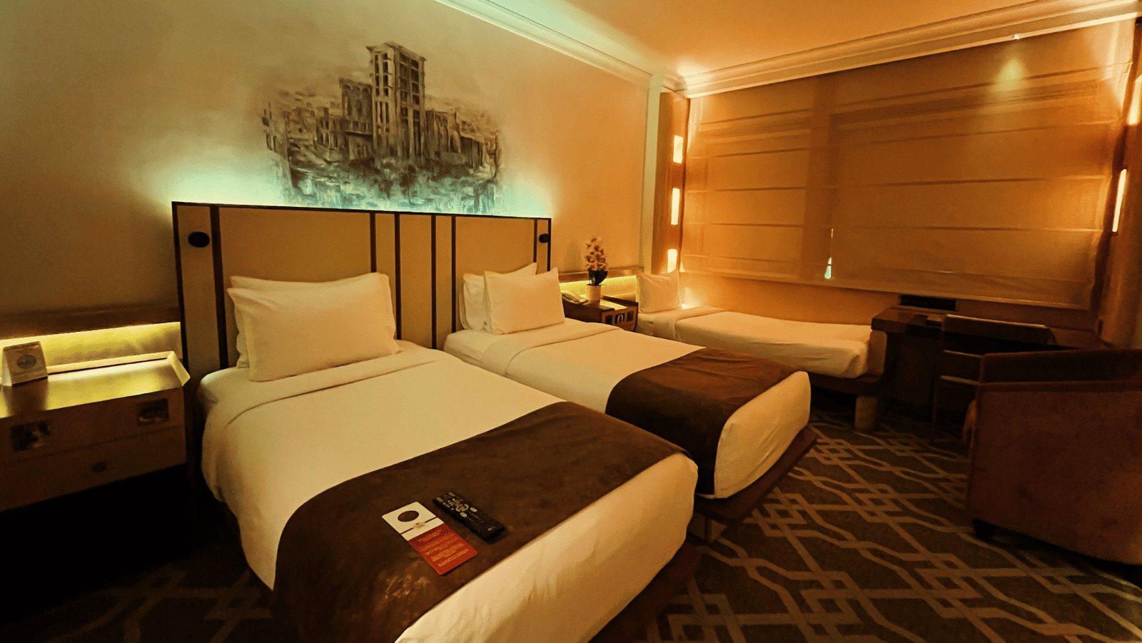 Two twin beds and a seating area and a single bed at the side of the room at Marco Polo Hotel.