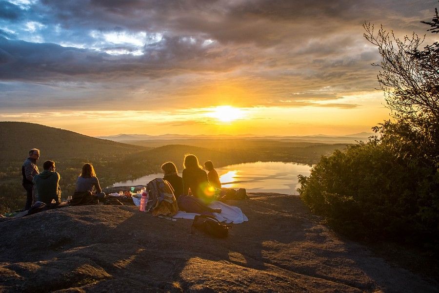 An eventful evening shot of a group of people watching the sunset at a distance on top of a hill