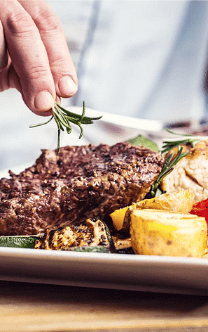 A close up shot of a chef preparing a meal at Nirvana Luxury Hotel, Ludhiana.