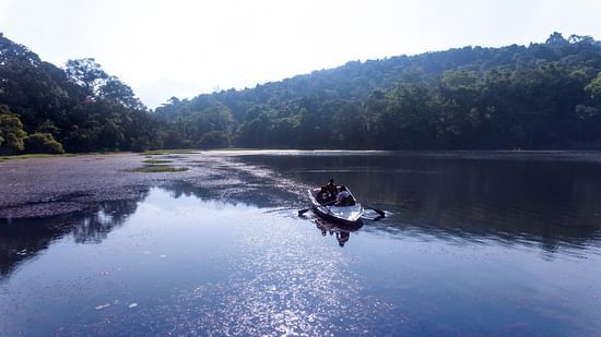  A boat is on a lake with trees and mountains in the background.