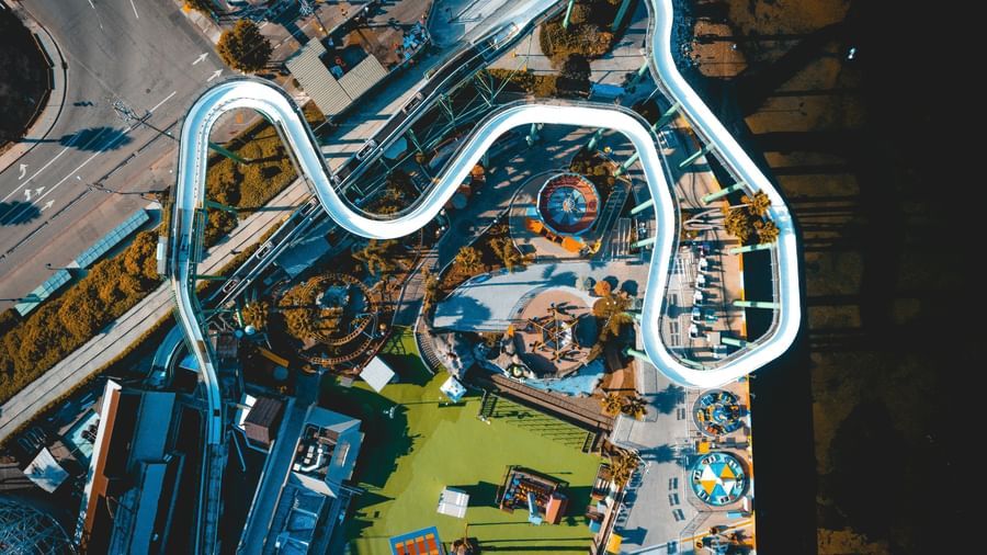 A bird's-eye view of a white, winding, roller coaster-like water slide at a water park. 
