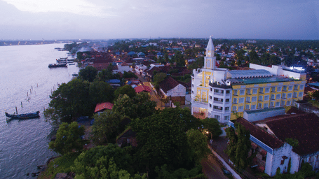 Aerial view of the hotel with the sky and beach in the background, surrounded by trees