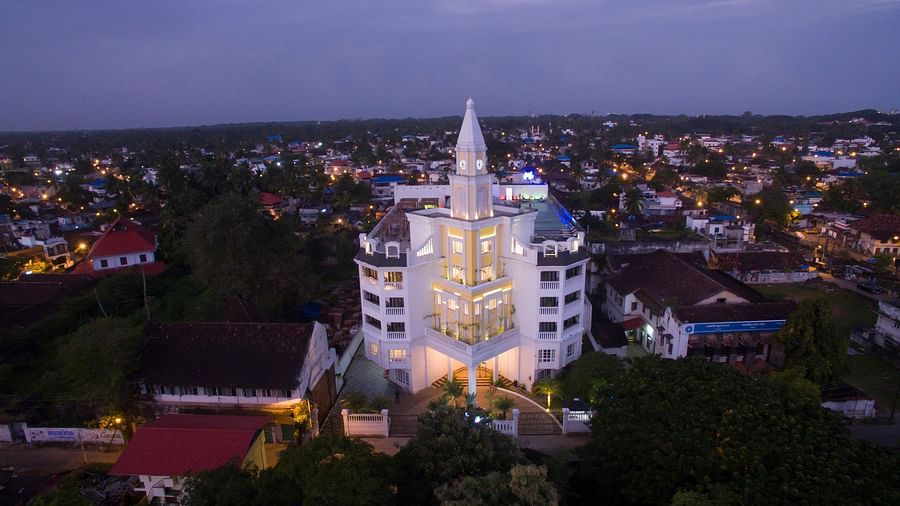  Facade view of the hotel surrounded by trees and illuminated by highlighted building lights against the night sky