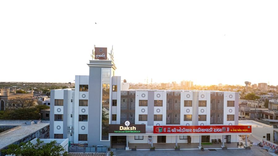 Front view of Daksh The Grand Gowardhan, Dwarka, bathed in the morning light, showcasing its modern architecture and entrance.