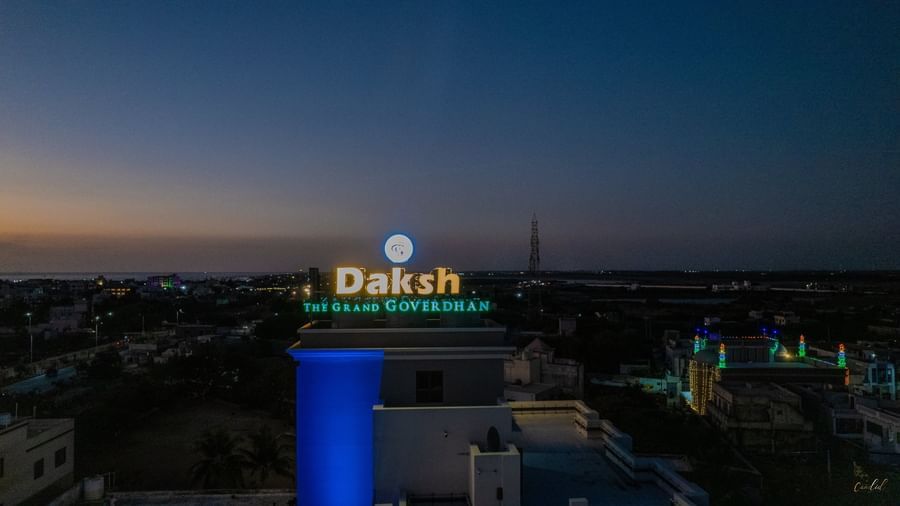 The signboard of Daksh The Grand Gowardhan, Dwarka, illuminated at twilight visible against the darkening sky.