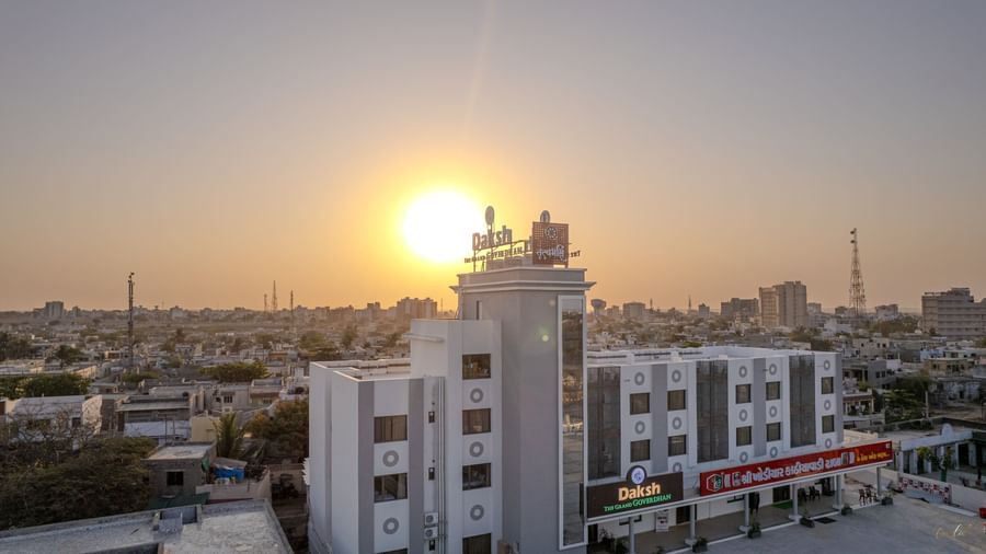 Aerial view of Daksh The Grand Gowardhan, Dwarka, at sunset, with the building silhouetted against the vibrant sky.