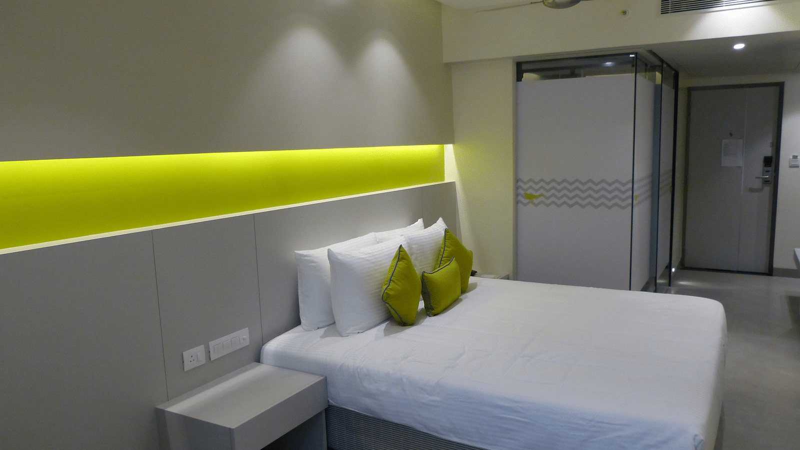 Spacious bed with headboards stretch across the wall with door way leading to the  next room