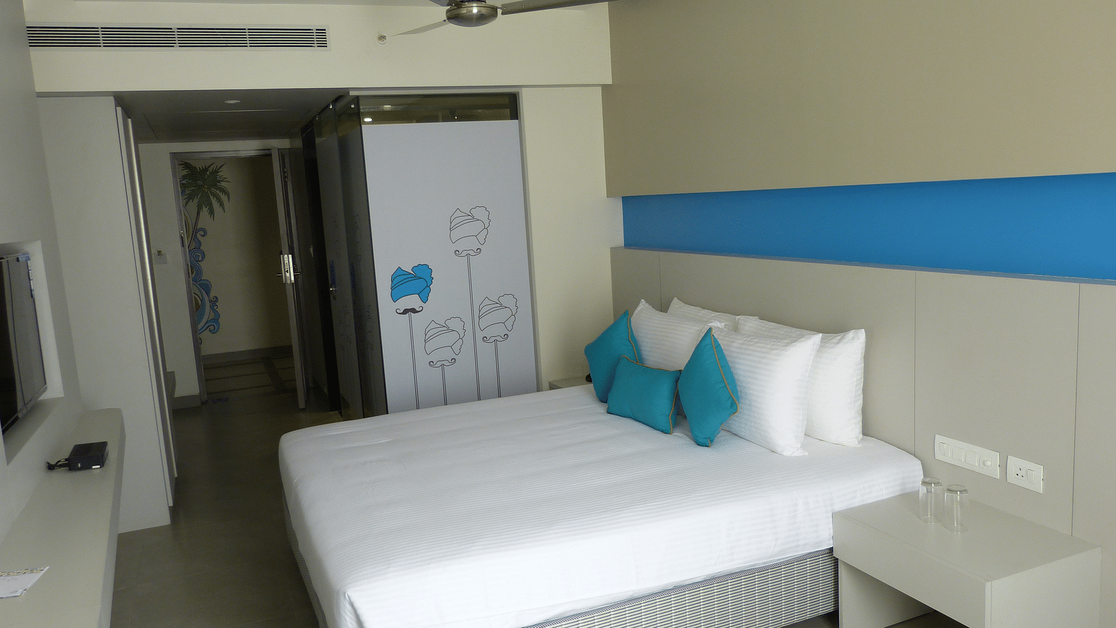 Spacious bed with headboards stretch across the wall with door way leading to the  next room
