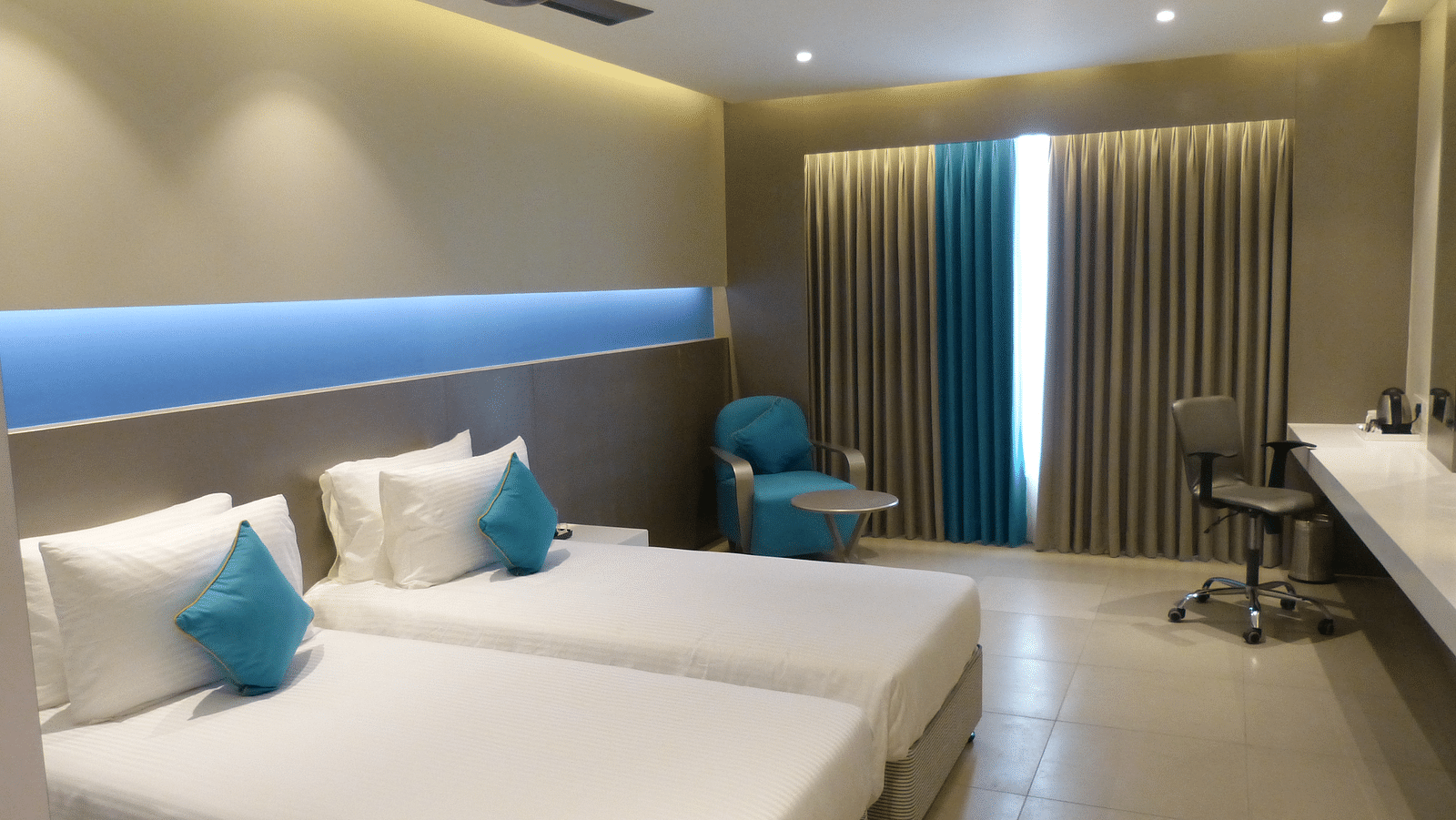  Spacious twin beds with headboards stretch across the wall, and large windows with curtains cover them