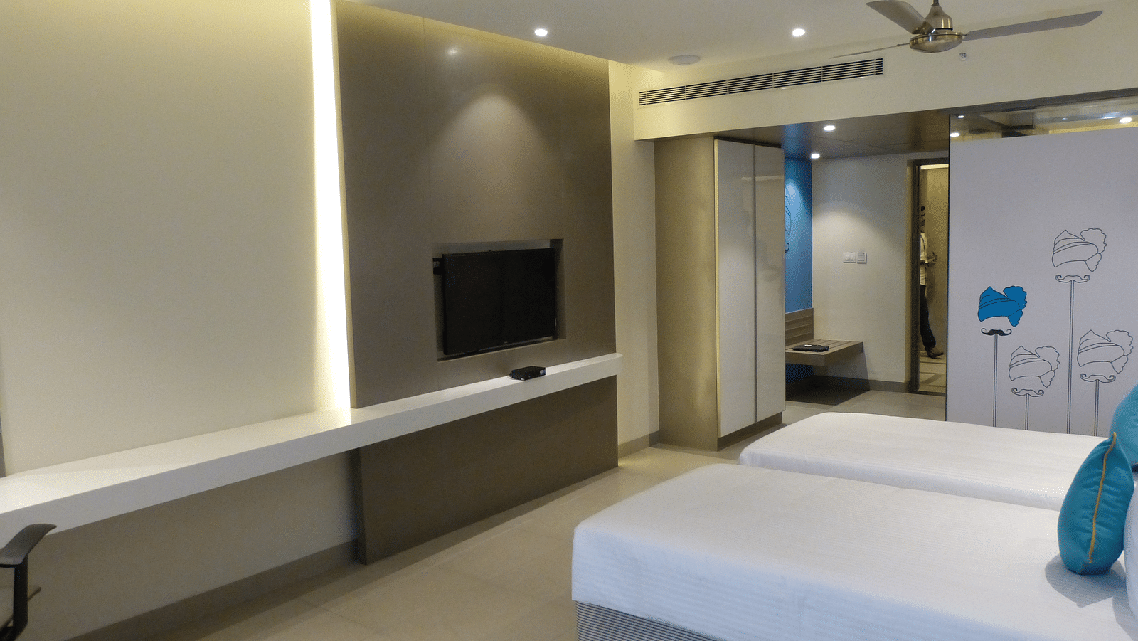 A twin bed faces a wall-mounted television directly opposite