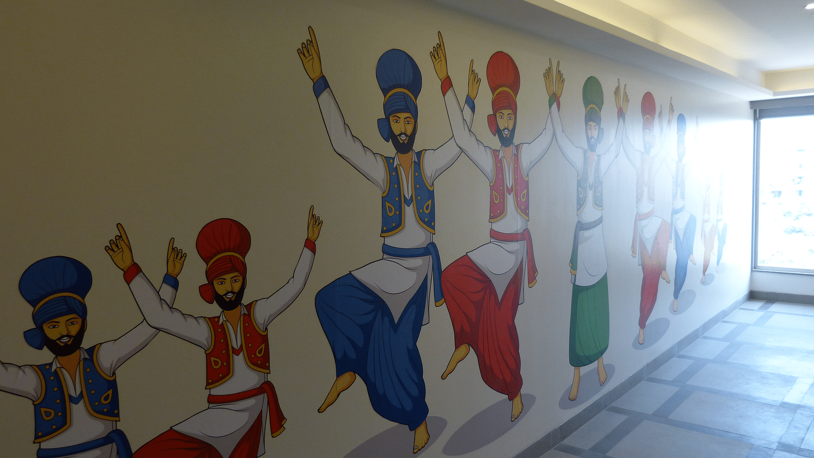 Men in Punjabi attire dancing are painted on the wall