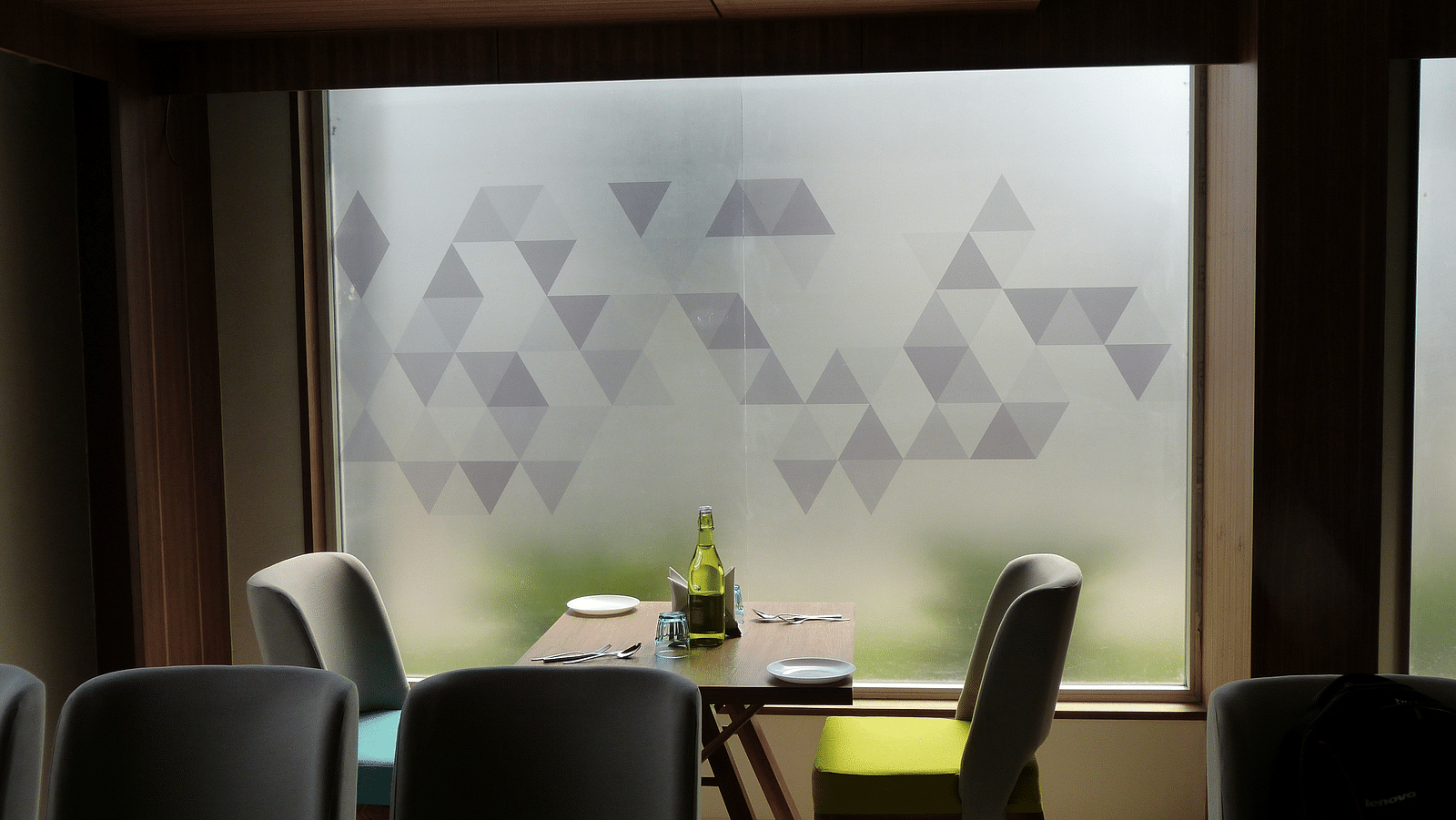 The table is neatly set with cutlery, and two seats are placed on each side, next to the window