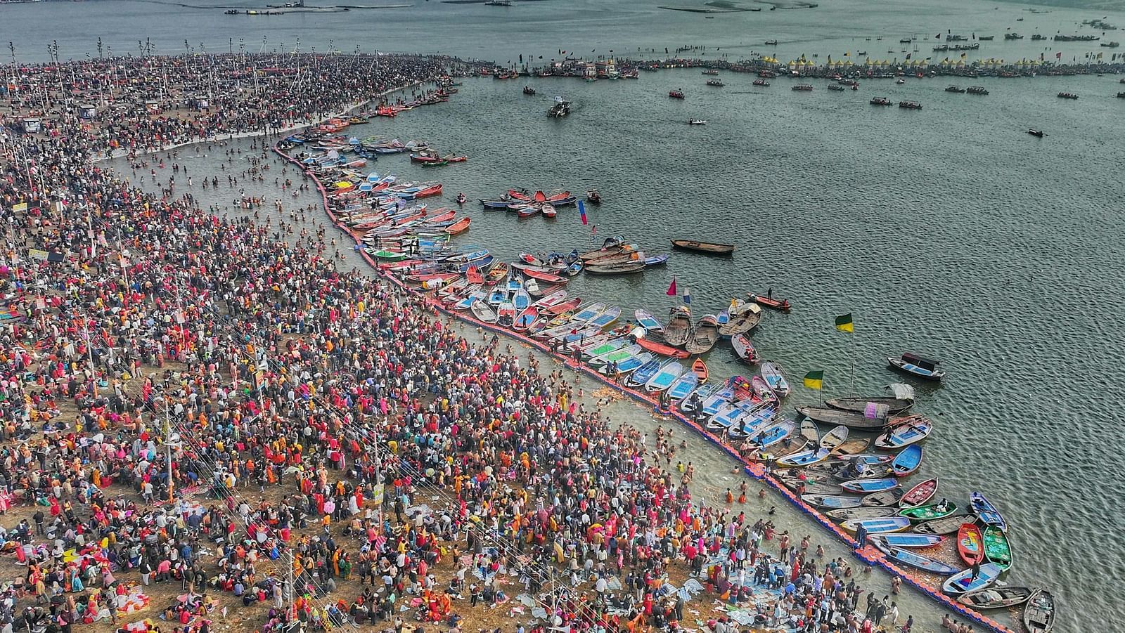 Aerial view of a crowded riverside gathering with boats and people - Triveni Sangam.