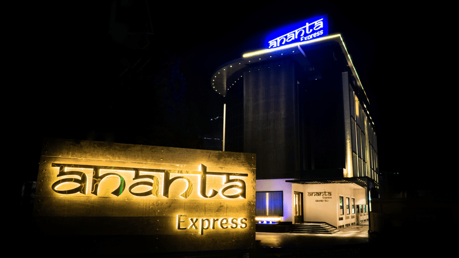 A nighttime view of the hotel facade featuring illuminated Ananta Express branding and warm building lights at Ananta Express, Katra.