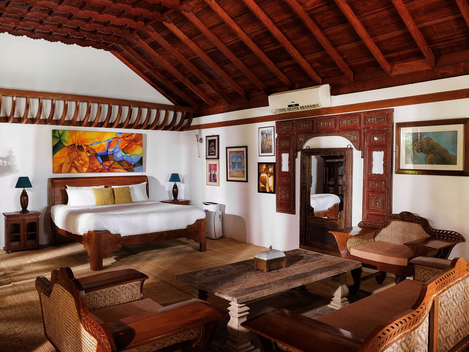 A wooden interior room with wooden furnitures such as a bed, a sofa set, a coffee table, and paintings - BluSalzz Villas - Muhamma Resort, Alleppey