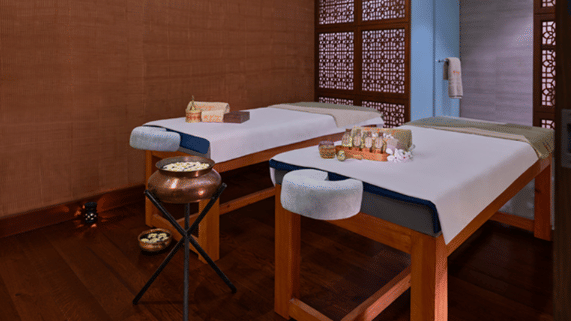 An overview of a spa room featuring two beds at the Iyãsya Spa with various spa essentials kept on display at The Resort, Mumbai.