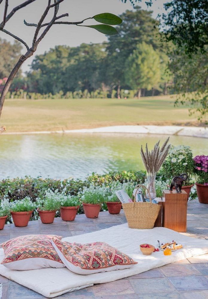Table setup by the lake at Karma Chalets with potted plants, some food items, and outdoor scenery in the background.