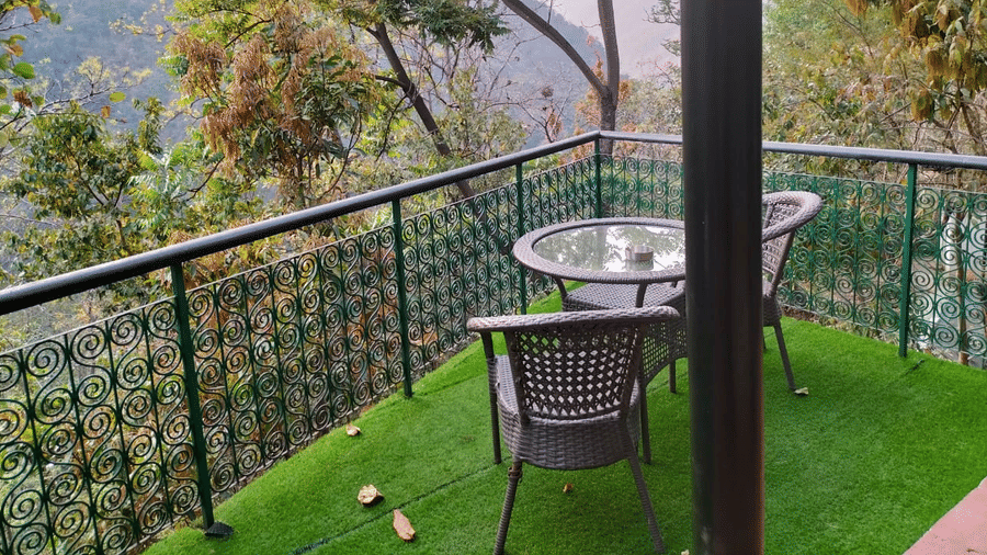 Private outdoor balcony with seating overlooking lush greenery and river valley views offering a peaceful sit out experience at Neemrana’s Glasshouse on The Ganges ideal for enjoying fresh air and natural surroundings