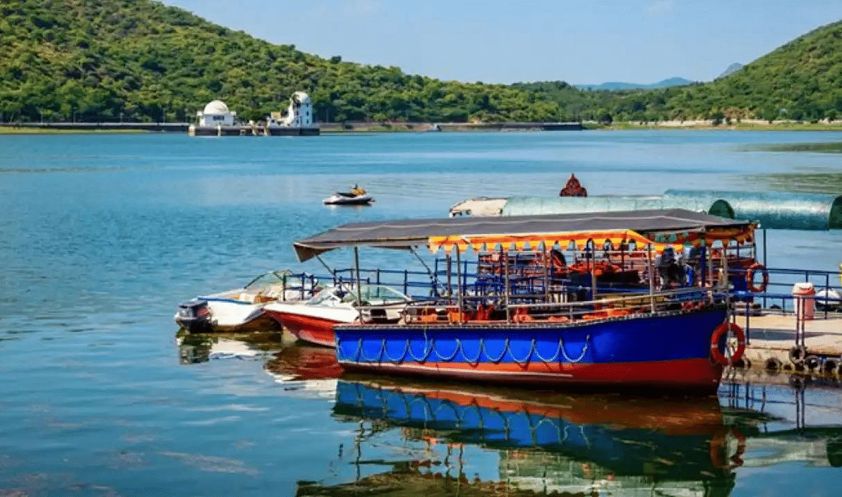 Lake with tourist boat, hills in background.