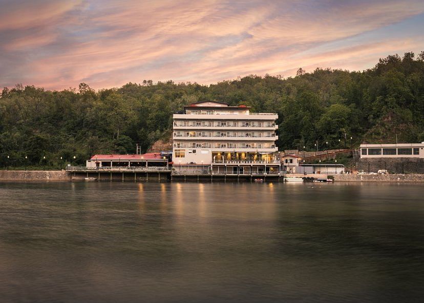 A huge building with a restaurant overlooking a calm lake at sunset.