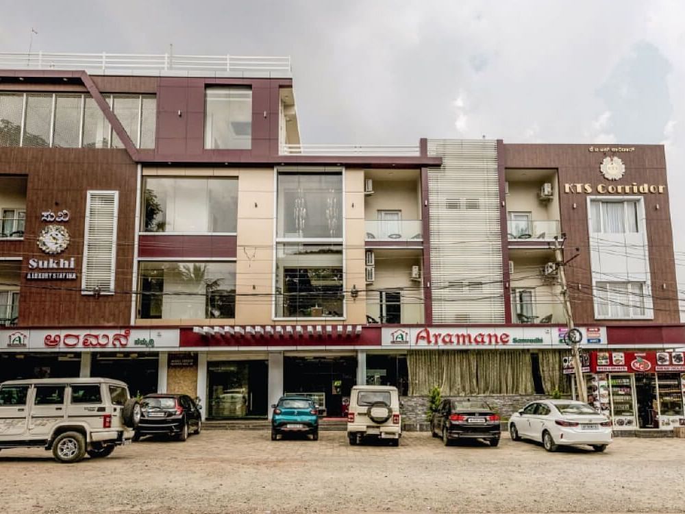 Facade image of Sukhi - A Luxury Stay Inn, Chikkamagaluru with several vehicles parked in the front.