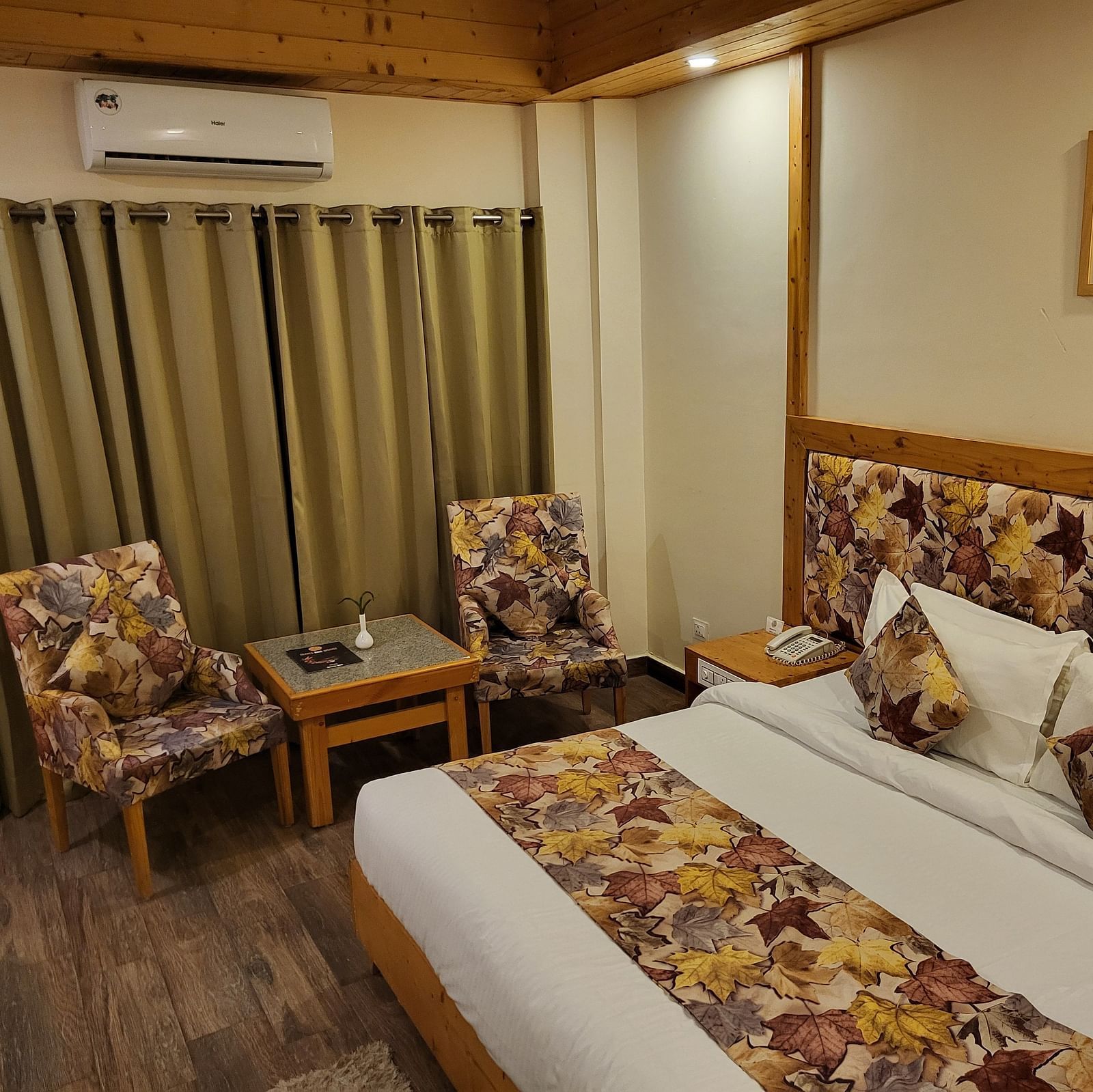 Side angle of the bedroom, featuring comfortable seating, elegant curtains, and wooden flooring at Dagshai Manor Kasauli - Inde Hotels.